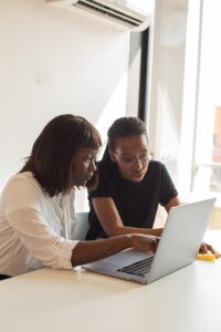 Two women looking at the same laptop